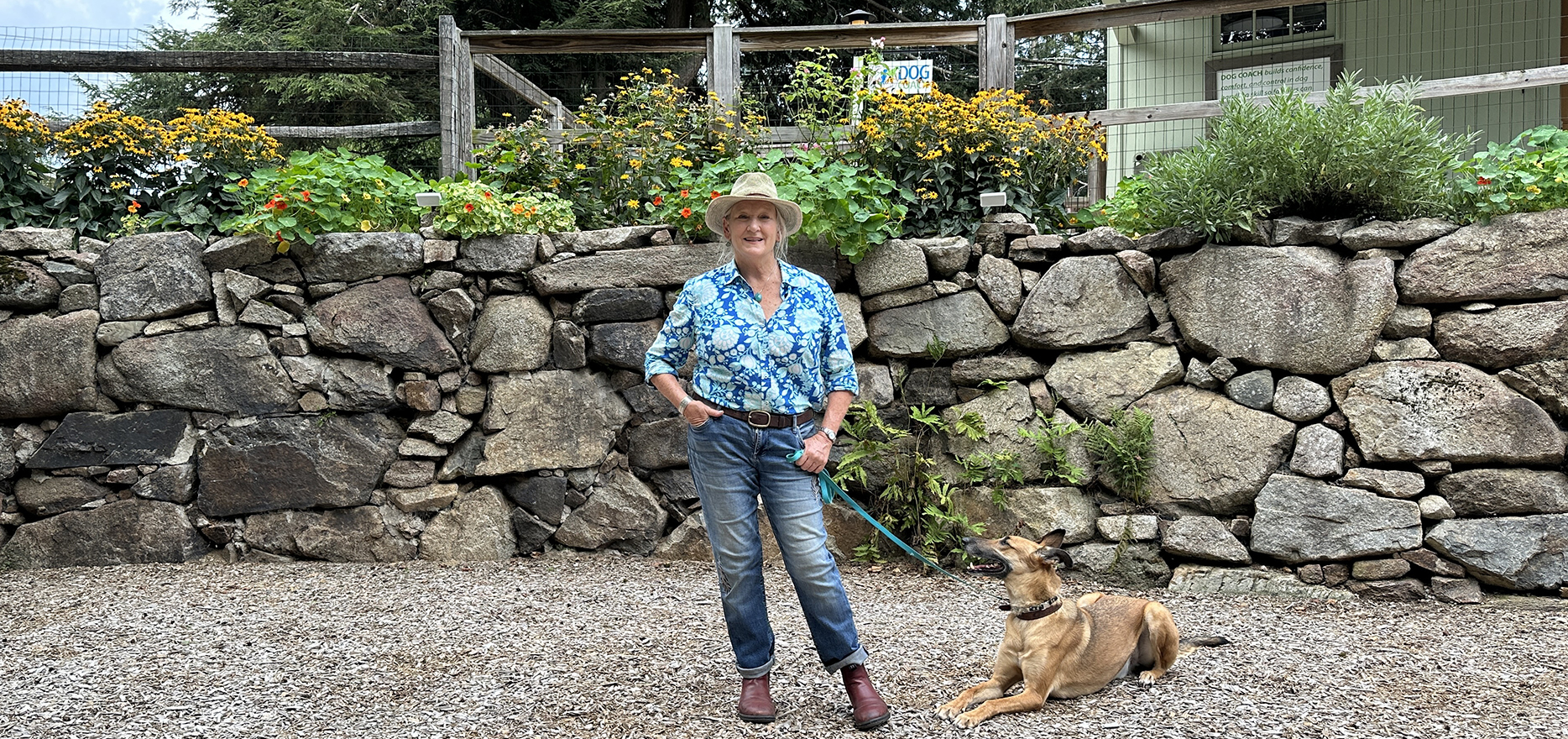 dog coach owner sarah prescott, a white woman in her 60s, poses with a dog at their facility